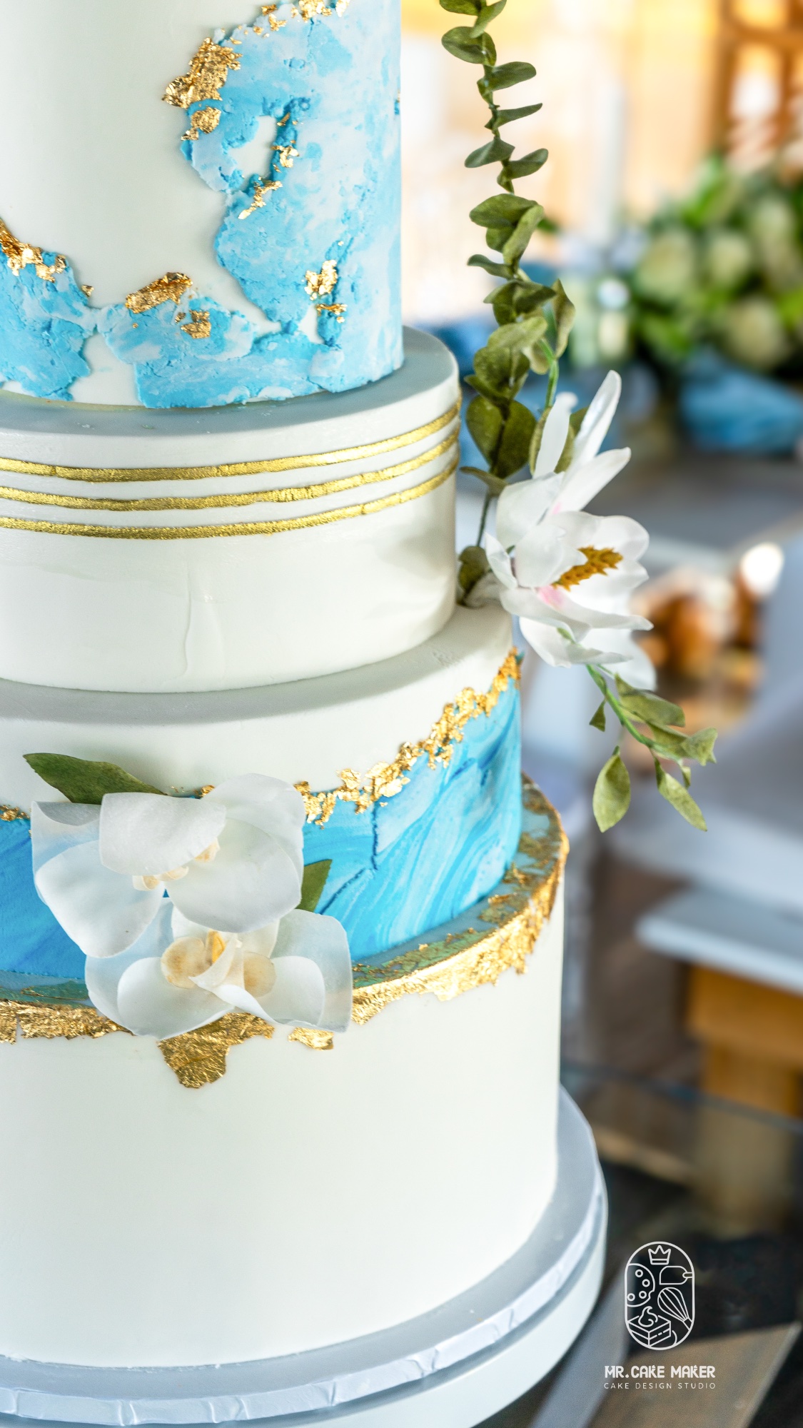 Detail of hand-crafted sugar orchids and gold leaf on wedding cake tier